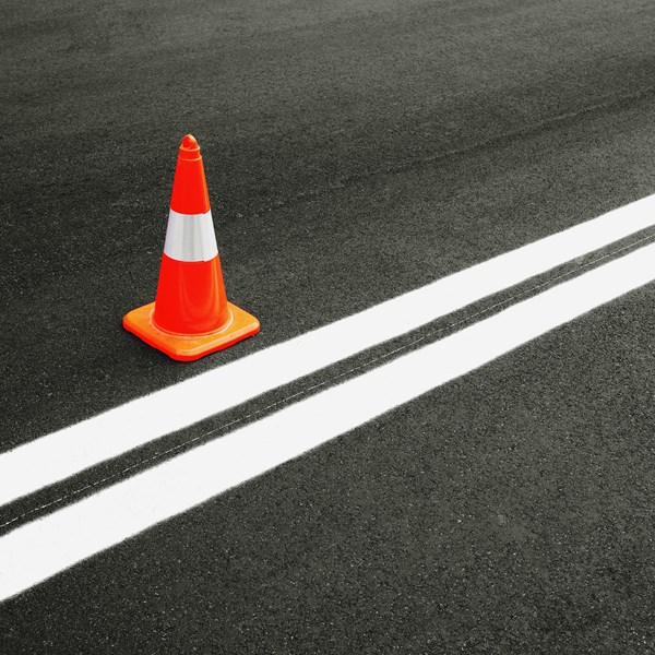 Traffic cone on ashalt next to reflective white traffic lines painted with paint utilizing LUMINEX C ultrawhite durable filler to achieve the purest of color effects.