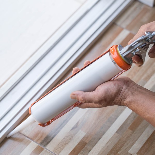 Construction worker applying caulk or sealant around windows, sealant utilizes SNOBRITE air floated kaolin offering excellent color quality, surface finish, permeability, scrub resistance and hiding power.