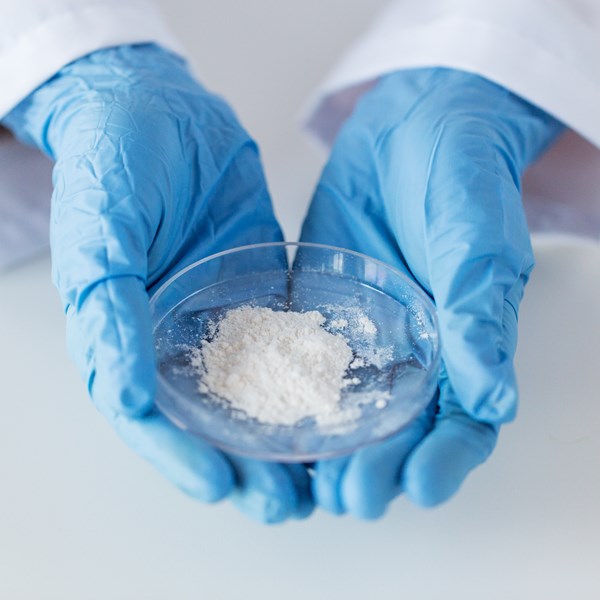 Scientist in lab holding petri dish of bright white LUMINEX C ultrawhite durable filler made from nepheline syenite.