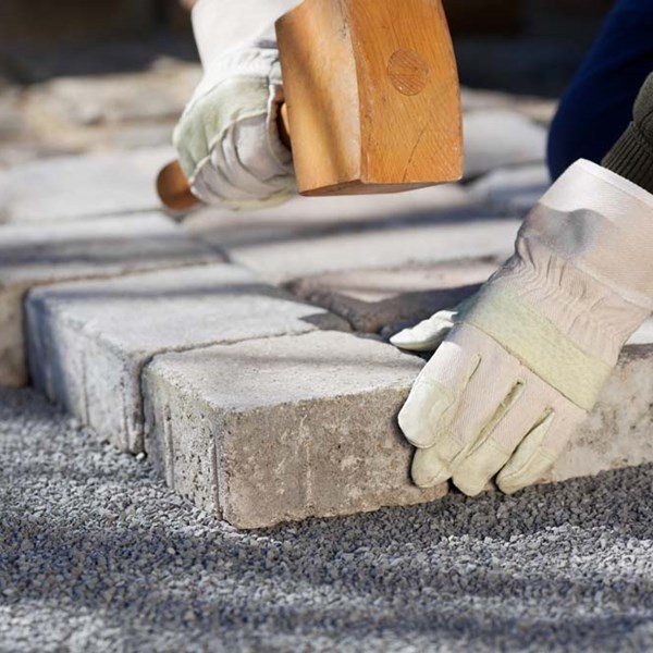 Landscaper laying pavers with GRANUSIL HS hardscape angular sand for path or patio installation using small fines and large aggregate for level surface, strong foundation make jointing, bedding and gradation easy.