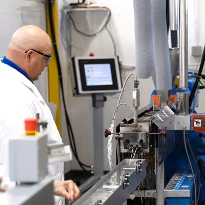 High technology modern Covia Coating and Polymers laboratory showing lead lab technician manager using twin extruder machinery to create pellets for use in plastics and elastomers markets.